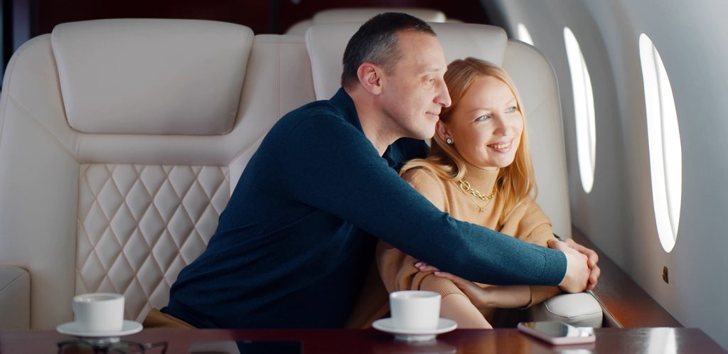 Happy couple relaxing in private jet enjoying travelling together by plane.